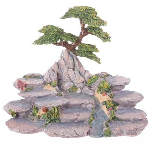 Angled view of a Flower Fairy World Figures display stand, featuring a rocky tiered landscape with green foliage, a central stream, and a bonsai tree at the peak.