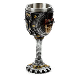 Front view of a decorative Steampunk Skull Goblet. The metallic grey and black goblet features a prominent skull wearing a top hat and goggles, surrounded by intricate bronze gear and pipe detailing. It has a stainless steel inner cup and a screw-threaded stem on a cog-shaped base.