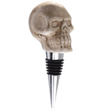 Angled profile view of a glossy, bone-coloured ceramic skull bottle stopper, with a silver-coloured metal base and black rubber seals.