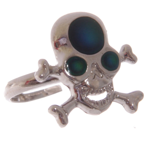 Angled view of a shiny, silver-coloured mood ring featuring a skull and crossbones design. The skull has a large, dark, iridescent mood stone on its forehead and bright green eye inserts.