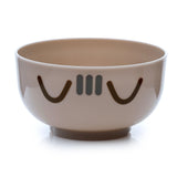 Angled view of a round, light beige bowl featuring dark brown Pusheen cat face details, part of a bento lunch box.