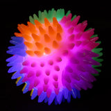 Front view of a multicoloured spiky bouncy light-up ball glowing in the dark.