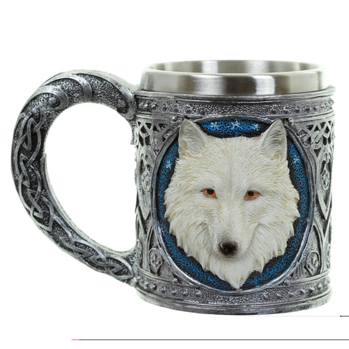 Angled view of a Collectable Decorative Wolf Tankard, showing an embossed white wolf head with orange eyes on a textured blue background, intricate silver Celtic knotwork on the handle and body, and a metallic interior.