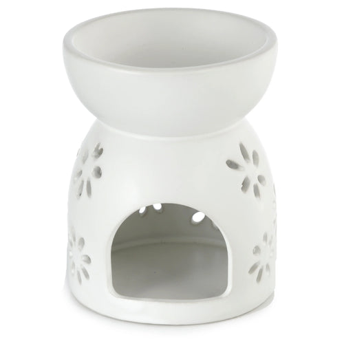 Angled view of a white ceramic oil and wax burner, featuring a top bowl, an arched opening for a tealight, and daisy cut-out patterns on the base.