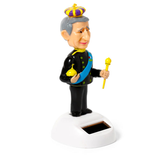 Front view of a solar powered King Charles pal figurine, wearing a purple and gold crown, black suit with a blue sash, holding a gold orb and scepter, on a white base with a solar panel.