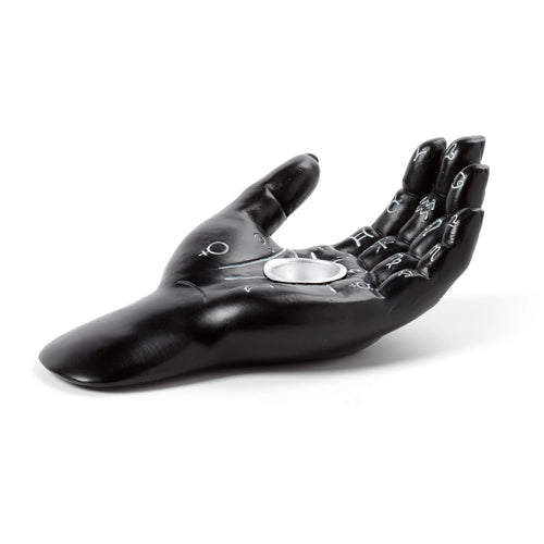 Angled view of a black decorative hand-shaped incense cone dish, featuring white mystical symbols on its upward-facing palm and fingers, and a silver-coloured incense holder in the centre.