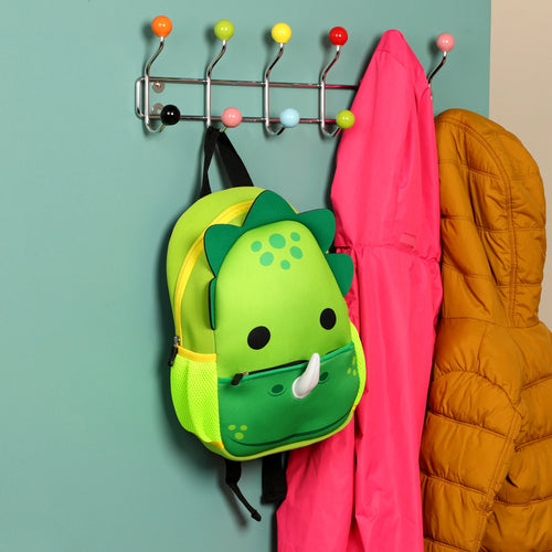 Front view of a green dinosaur neoprene kids school backpack, featuring a dinosaur face design and mesh side pockets, hanging on a colorful coat rack.
