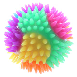 Front view of a vibrant multi-colored spiky bouncy ball, featuring sections of magenta, green, yellow, orange, blue, and purple, presented on a clean white background.