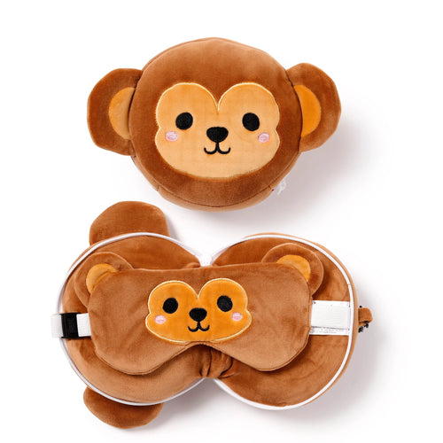 Overhead view of a brown plush monkey travel pillow and eye mask set, showing the round pillow with an embroidered monkey face and another unzipped to reveal the matching monkey eye mask with an adjustable white strap.