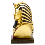Side view of a decorative gold Egyptian Tutankhamen bust figurine, featuring a striped headdress with cobra and vulture detail, and hieroglyphic symbols on its dark base.