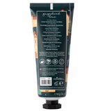 Back view of a dark teal moisturising hand cream tube with a Christmas gingerbread lane design featuring gingerbread houses, trees, and stars.