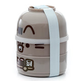 Front view of a round, stacked grey/taupe bento lunch box with a light blue elastic band, decorated with Pusheen the Cat's face and body designs.
