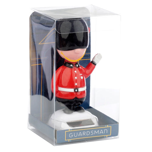 Front view of a novelty Solar Pal Guardsman figurine in clear retail packaging, featuring a red uniform, black bearskin hat, and raised hand, set against a white background.