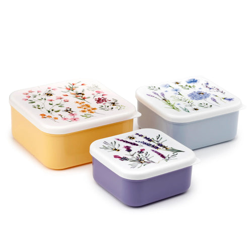 Angled view of a set of three rectangular lunch boxes in varying sizes. The largest is yellow, the mid-sized is light blue, and the smallest is purple. All feature white lids decorated with colourful floral patterns and bees.