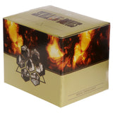Angled view of golden packaging for a figurine or ornament, showing the top, front, and left side. The top features 'SKULL & BONES' text. The front has orange flame-effect graphics, a hexagonal pattern with skull images, and the text 'RESIN ORNAMENT'.