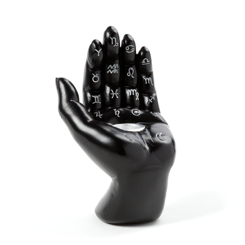Angled view of a black decorative hand incense cone burner, prominently displaying white astrological symbols on the palm and fingers, with a silver-coloured cone holder.