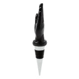 Side view of a novelty bottle stopper with a black raised hand top adorned with white mystic symbols, connected to a ribbed stopper base and silver tip.