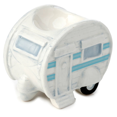 Angled view of a white ceramic caravan egg cup, decorated with light blue windows, door, and stripes, showing a black wheel on the side.