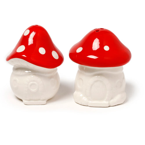 Angled view of a novelty ceramic toadstool salt and pepper set, featuring two shakers with bright red, white-spotted caps and cream-coloured bases sculpted with miniature fairy house details.