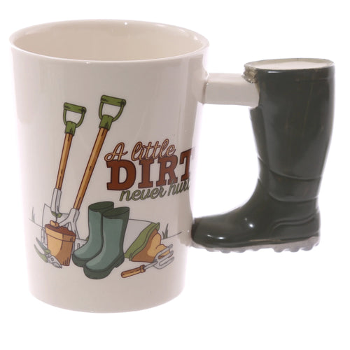Angled view of a white ceramic mug with a dark green Wellington boot-shaped handle. The mug features a garden-themed illustration with spades, green wellington boots, a plant pot, and the text 'A little DIRT never hurt'.