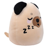 Light brown Gus the Pug Adoramals plush toy, angled to display its sleeping face with black embroidered eyes, pink cheeks, a brown nose, and black 'Zzz's, complemented by black floppy ears.