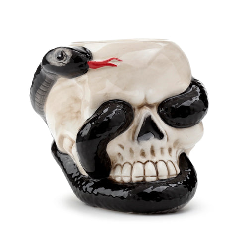 Three-quarter view of a ceramic oil burner shaped as an off-white skull, with a glossy black coiled snake featuring visible red fangs.