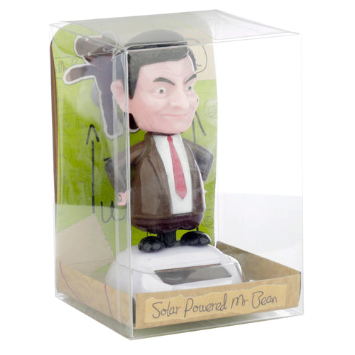 Front view of a Mr Bean solar-powered bobblehead figurine, wearing a brown suit and red tie, enclosed in clear retail packaging. The figurine stands on a white base with a visible solar panel. The packaging features a 'Solar Powered Mr Bean' label and a green background insert with a teddy bear illustration.
