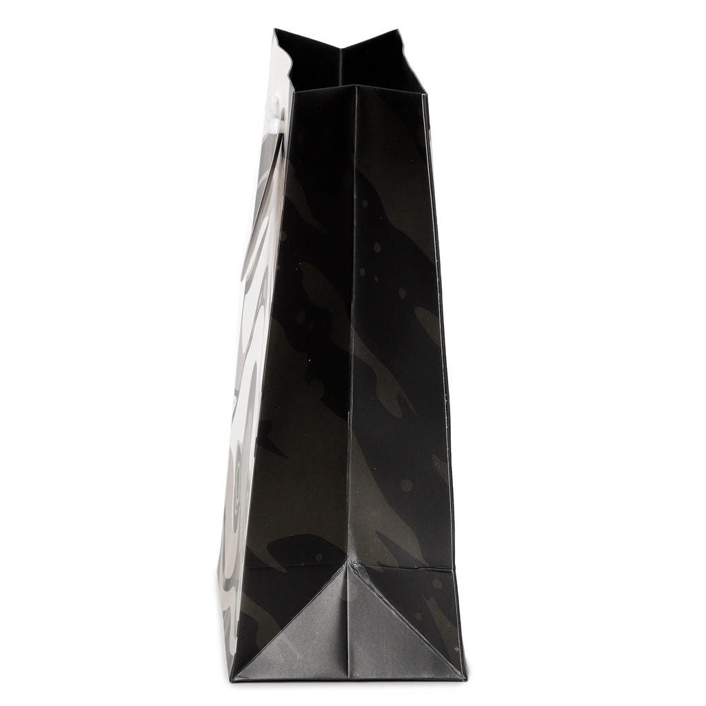 Side view of a black gift bag with white handles and a graphic pattern.