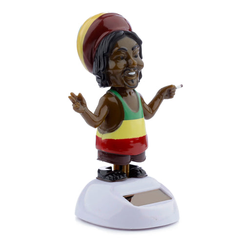 Angled view of a dark-skinned Rasta Solar Pal figure wearing a red, yellow, and green tam and vest. The figure makes a peace sign and holds a lit cigarette, standing on a white base with a solar panel.