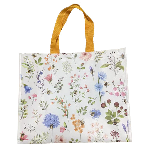 Full view of a white durable reusable shopping bag with a Nectar Meadows floral and bee pattern and yellow fabric handles.