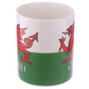 Angled view of a white and green porcelain mug, featuring a red Welsh dragon design and partially visible 'CYMRU' text.