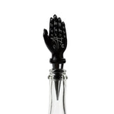 Front view of a black Mantric Hand Tarot Hand Palm novelty bottle stopper featuring white astrological symbols and palmistry lines, inserted into a clear glass bottle.