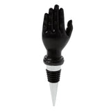 Front view of a black novelty bottle stopper shaped like an open hand with palm facing forward, featuring a black ribbed base and silver conical tip.