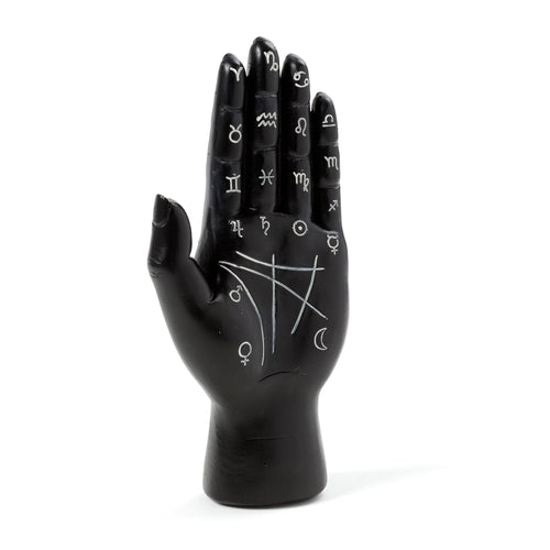 Black Tarot hand ornament, angled view, displaying white astrological symbols and palmistry lines on its palm.