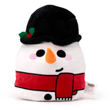 Front view of a white Squidglys plush snowman toy, featuring a black top hat with green holly and red berries, a red scarf, black eyes, an orange carrot nose, pink cheeks, a black smile, and two black buttons.