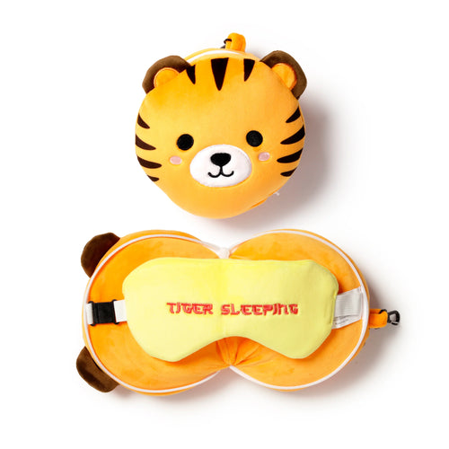 Overhead view of an orange plush tiger head alongside a matching orange round travel pillow and yellow eye mask embroidered with 'TIGER SLEEPING'.