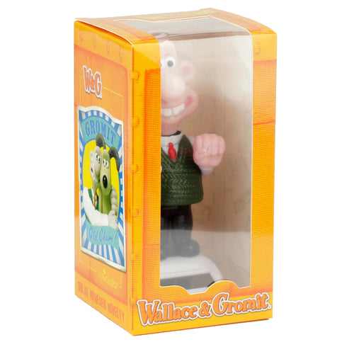 Angled front view of a Collectable Licensed Solar Powered Pal Wallace figure, contained within its orange and yellow retail box. The Wallace figure, wearing a green vest and red tie, is visible through a clear window, smiling with a clenched fist. The packaging features a 'Wallace & Gromit' logo.