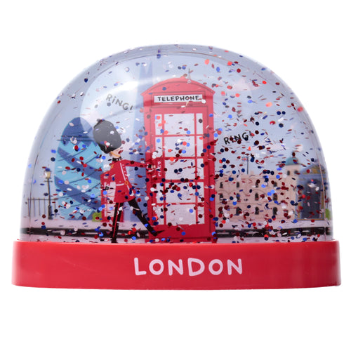 Front view of a London snow globe, featuring a Royal Guardsman and a red telephone box inside with red, white, and blue glitter confetti. It stands on a red base inscribed with 'LONDON'.