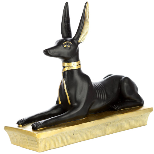 Angled view of a decorative gold and black Egyptian Anubis jackal figurine ornament in a lounging pose, on a white background.