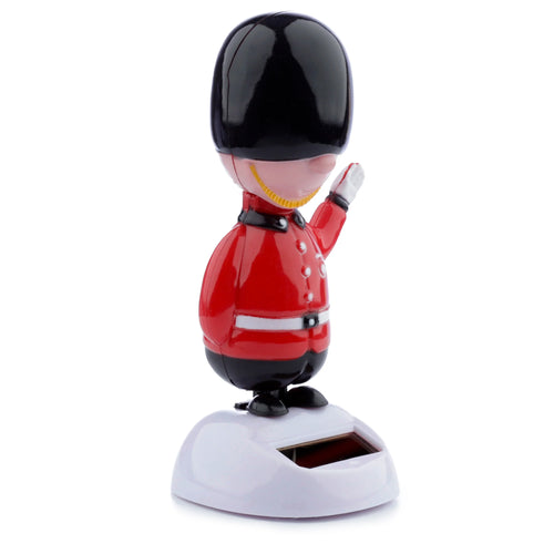 Front-angled view of a Fun Novelty Solar Pal Guardsman in a red uniform with a black hat, waving, on a white base featuring a solar panel.