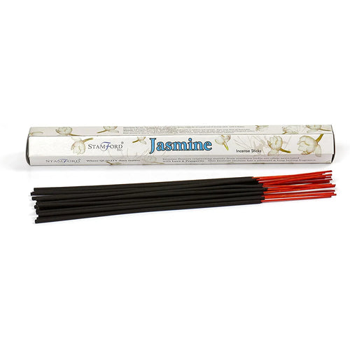 A light-coloured, hexagonal incense stick box, featuring 'Jasmine' text and delicate jasmine flower illustrations, is positioned upright behind a bundle of black incense sticks with vibrant red tips, laid out horizontally on a white background.